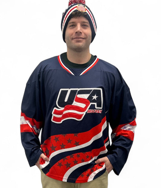 Man wearing a navy blue USA Hockey jersey and a matching knit beanie