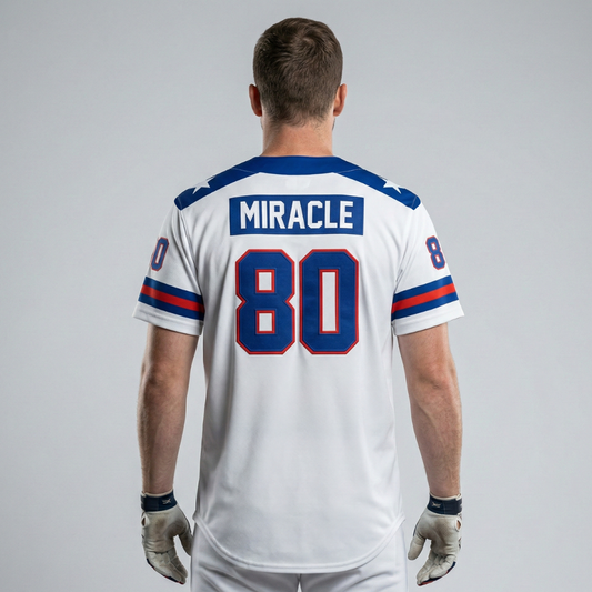 Back view of a person wearing a white baseball jersey with the name MIRACLE and number 80 in blue and red