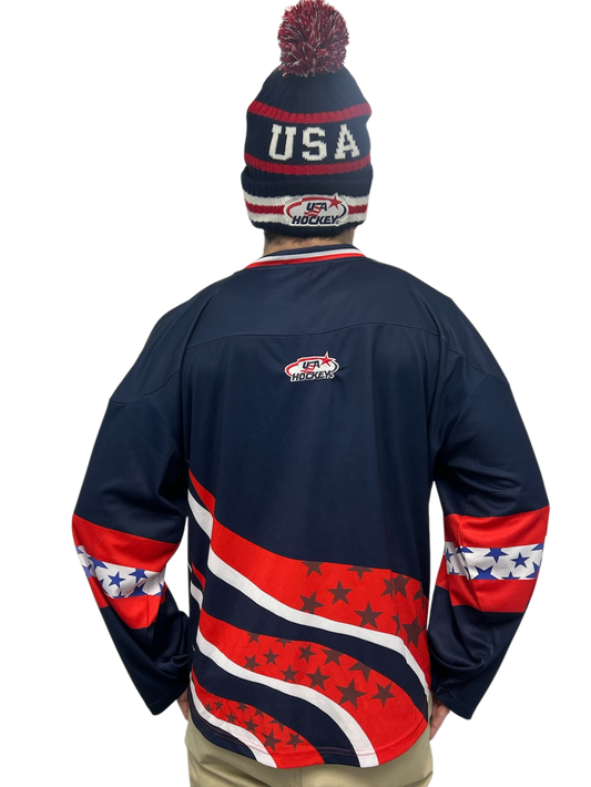 Person wearing a USA Hockey beanie and a navy blue jersey with red and white star patterns