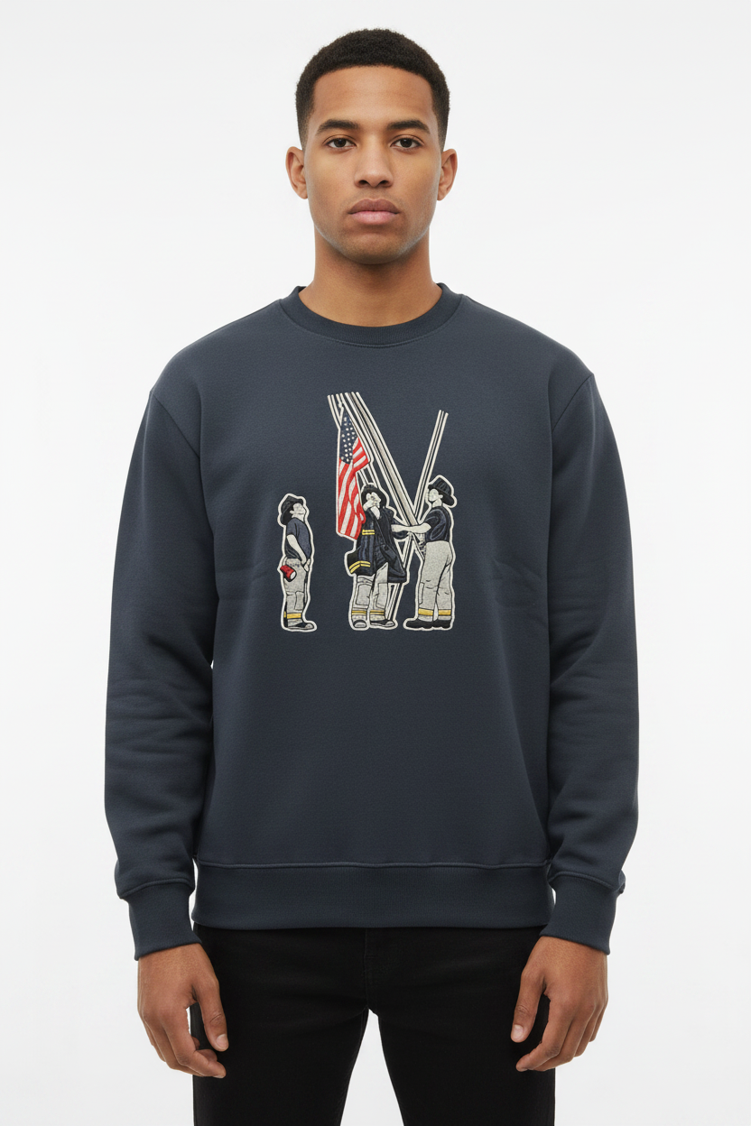 Man wearing a dark grey crewneck sweatshirt with a graphic of three firefighters raising an American flag
