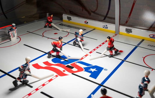 Tabletop hockey game with USA and Canada team figures on a white rink