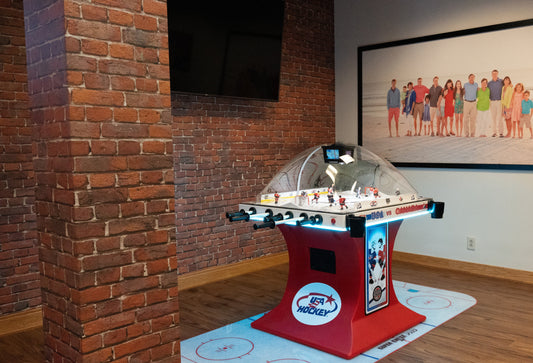 Super Chexx Pro USA vs Canada bubble hockey game on a branded floor mat in a room with brick walls