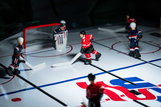 Tabletop hockey game with miniature players on a rink