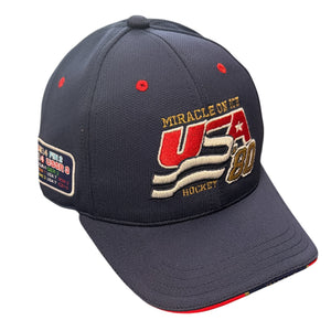 A dark navy blue baseball cap featuring embroidered 'MIRACLE ON IT USA 80 HOCKEY' text on the front panel, with red and gold accents. A rectangular patch is visible on the side.