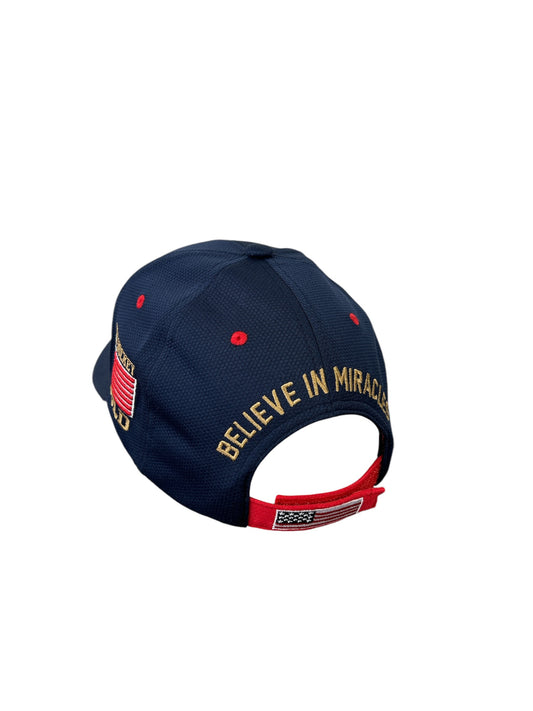 Navy blue baseball cap with Believe In Miracles embroidered in gold and a small American flag on the red strap